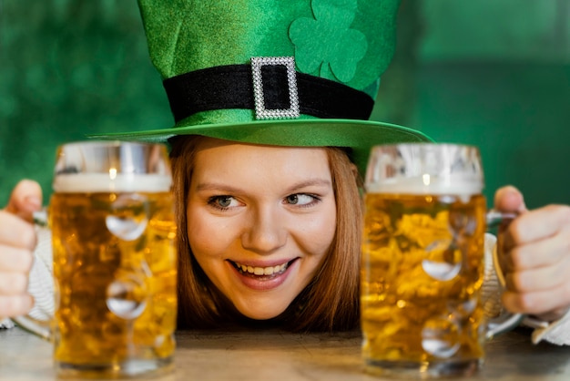 Smiley femme célébrant st. patrick's day au bar avec boissons