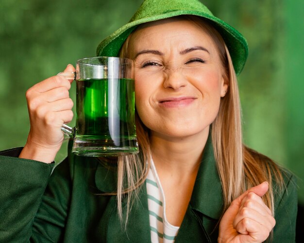 Smiley femme avec chapeau célébrant st. patrick's day avec boisson au bar