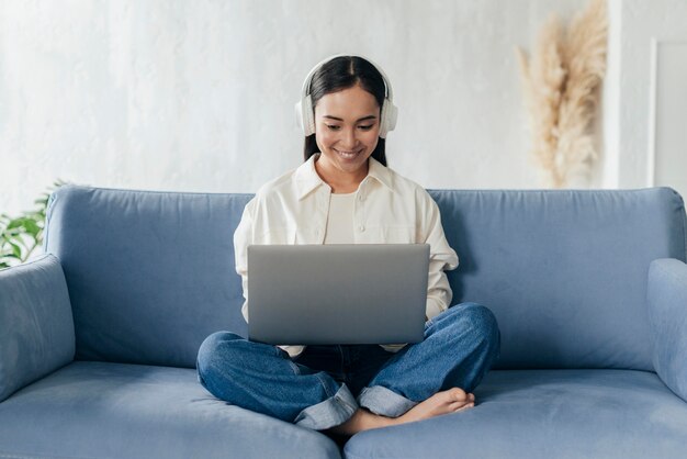 Smiley femme avec des écouteurs travaillant sur ordinateur portable