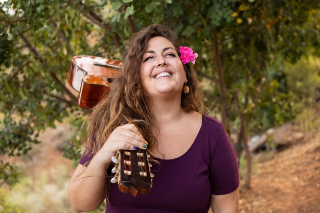 Smiley femme à l'extérieur portant guitare