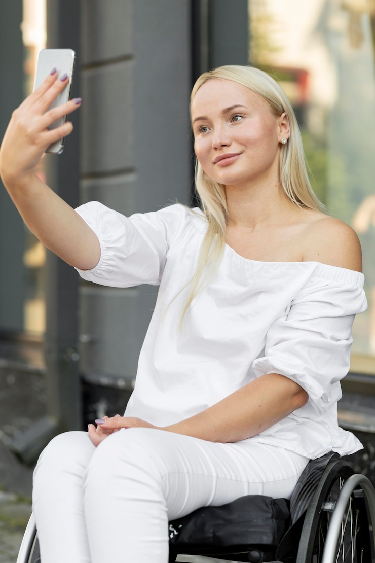 Photo gratuit smiley femme en fauteuil roulant prenant selfie avec smartphone