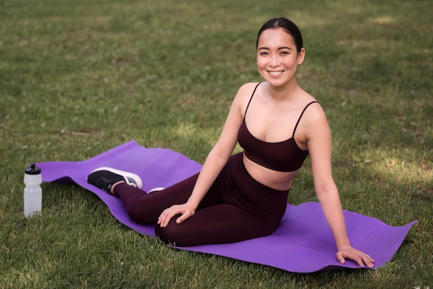 Photo gratuite smiley femme heureuse de pratiquer le yoga en plein air