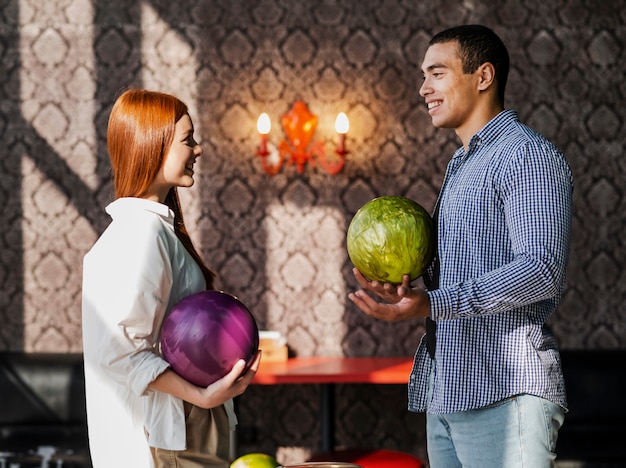 Photo gratuite smiley femme et homme tenant des boules de bowling colorées