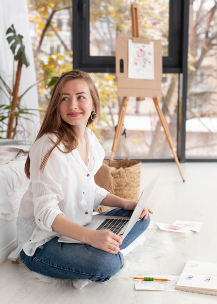 Smiley femme avec ordinateur portable sur ses genoux