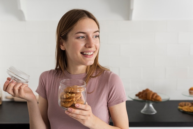 Smiley femme ouvrant un pot avec des cookies