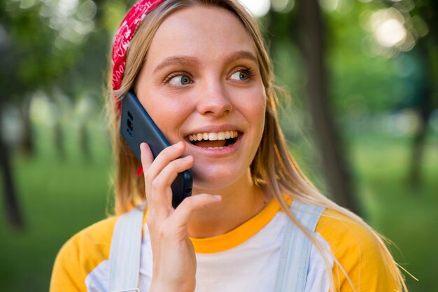 Smiley femme parlant au téléphone à l'extérieur