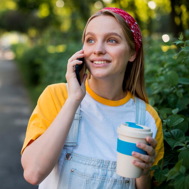 Smiley femme parlant au téléphone à l'extérieur
