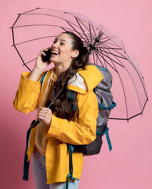 Smiley femme parlant au téléphone tout en tenant un parapluie