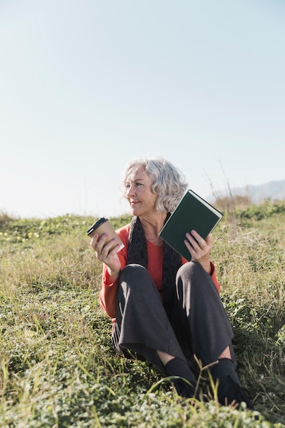 Smiley femme plein coup avec livre à l'extérieur