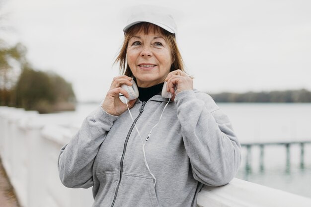 Smiley femme plus âgée avec un casque à l'extérieur tout en travaillant