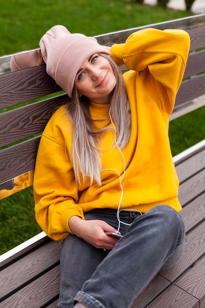 Photo gratuite smiley femme posant sur un banc tout en portant un bonnet