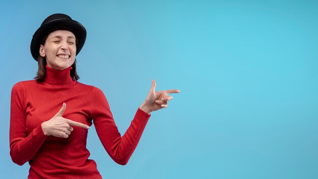 Smiley femme posant avec un chapeau tout en pointant