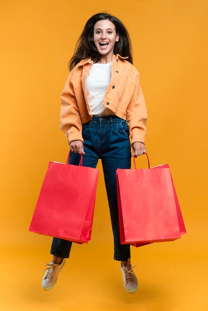 Smiley femme posant en sautant et tenant des sacs à provisions