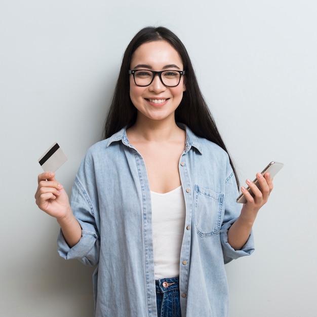 Smiley femme posant tout en tenant le smartphone et la carte de crédit