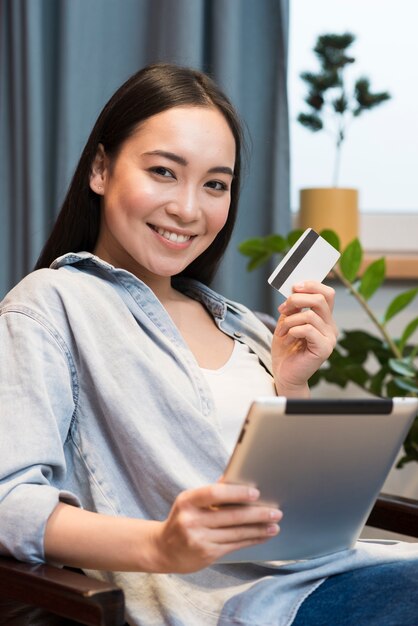 Smiley femme posant tout en tenant la tablette et la carte de crédit