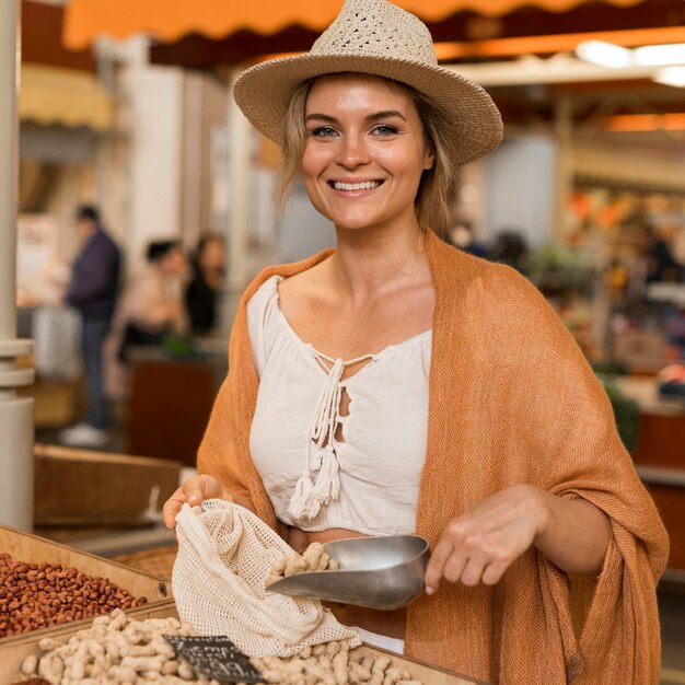 Smiley femme prenant des aliments séchés à la place du marché