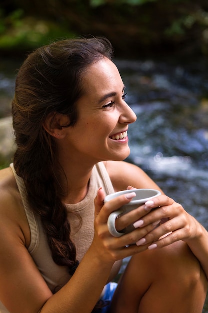 Photo gratuite smiley femme prenant un café tout en explorant la nature