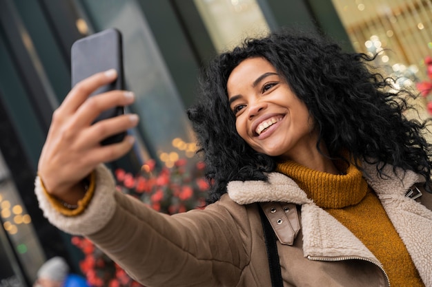 Photo gratuite smiley femme prenant un selfie avec son smartphone à l'extérieur