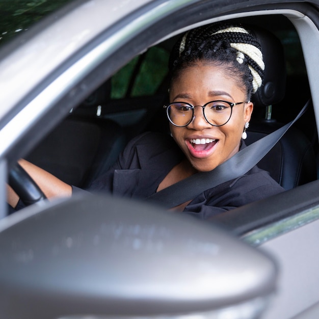 Smiley femme regardant dans son miroir de voiture