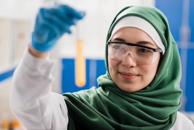 Smiley femme scientifique avec hijab tenant une substance