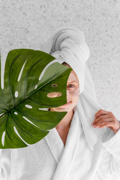 Smiley femme tenant une feuille de monstera