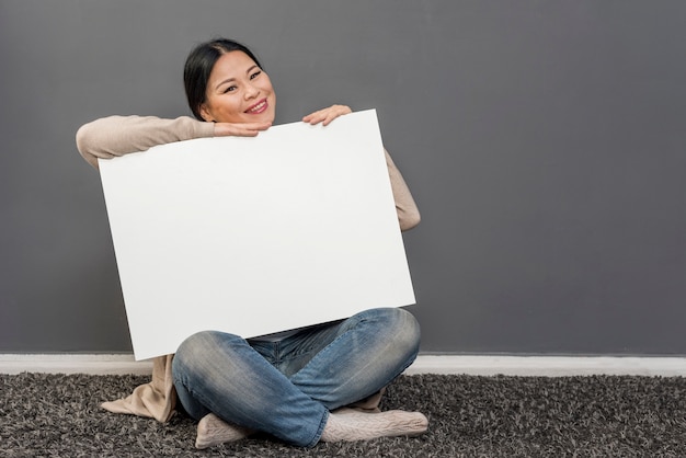 Smiley femme tenant une feuille de papier vierge