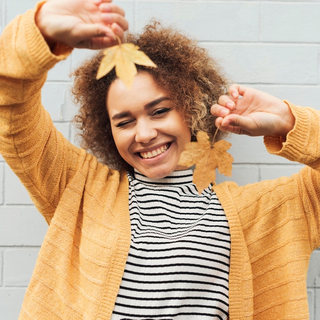 Photo gratuite smiley femme tenant des feuilles d'automne