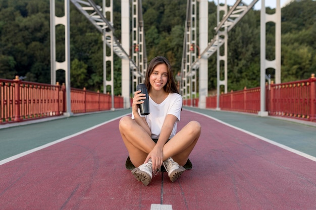 Smiley femme avec thermos posant sur le pont lors d'un voyage