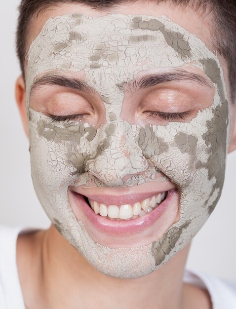 Smiley femme avec un traitement de boue sur le visage