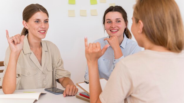 Smiley femmes conversant à table en utilisant la langue des signes