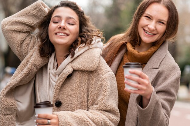 Smiley femmes avec des tasses à café à l'extérieur