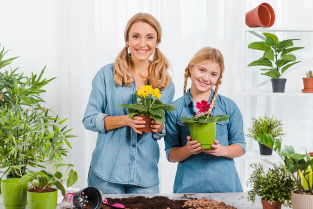 Smiley fille et maman tenant le pot de fleurs