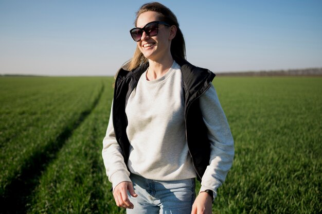 Smiley girl in the field portant des lunettes de soleil