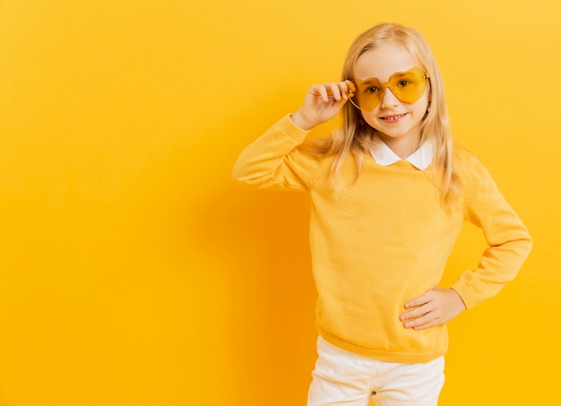 Smiley girl posant tout en portant des lunettes de soleil