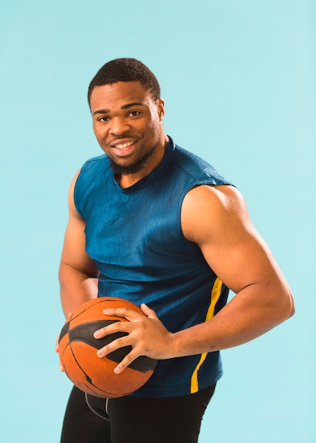 Photo gratuite smiley homme athlétique en tenue de gym tenant le basket-ball