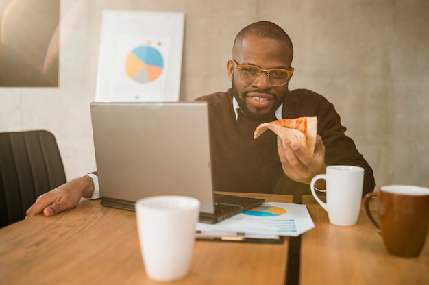 Smiley homme ayant une pizza lors d'une pause de réunion de bureau