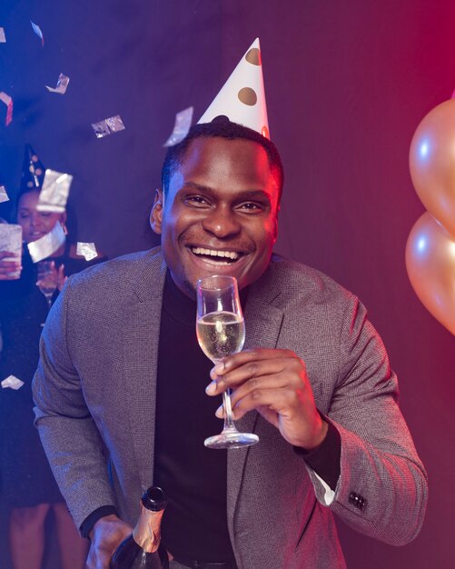 Smiley homme portant un chapeau de fête et tenant un verre