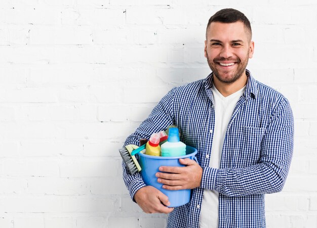 Smiley homme posant avec des produits de nettoyage et copie espace