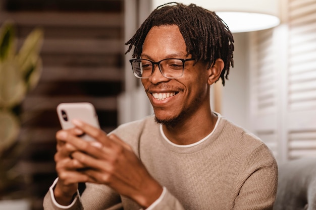 Smiley homme utilisant un appareil smartphone moderne à la maison