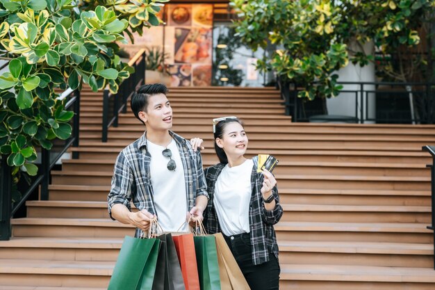 Smiley jeune couple tenant plusieurs sacs à provisions en papier