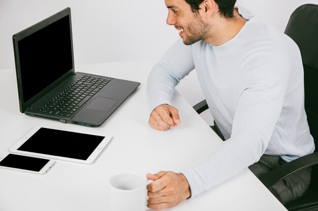 Smiley man avec des dispositifs technologiques et une tasse à café