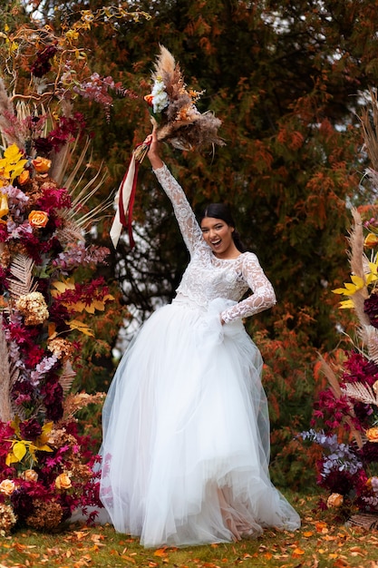 Photo gratuite smiley mariée posant avec des fleurs plein coup