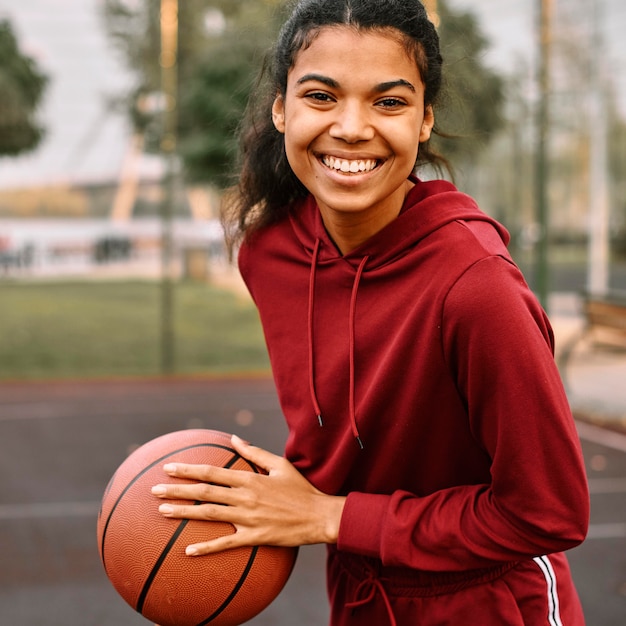 Smiley noir femme américaine tenant un ballon de basket