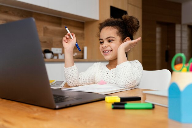 Smiley petite fille à la maison pendant l'école en ligne
