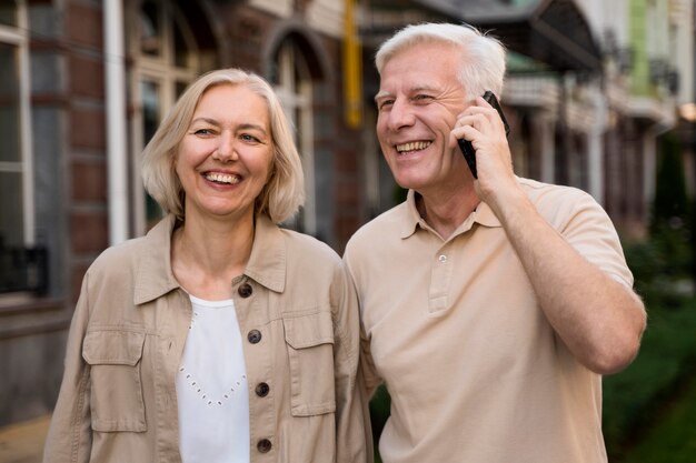 Smiley senior couple à l'extérieur tout en prenant sur smartphone