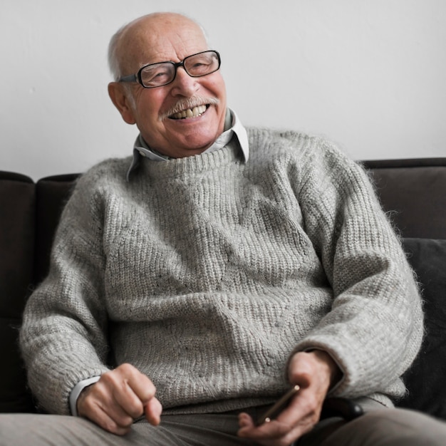 Smiley senior man dans une maison de soins infirmiers holding smartphone