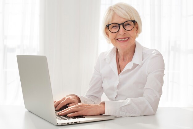 Smiley senior travaillant sur un ordinateur portable