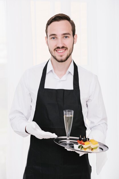 Smiley serveur présentant du champagne