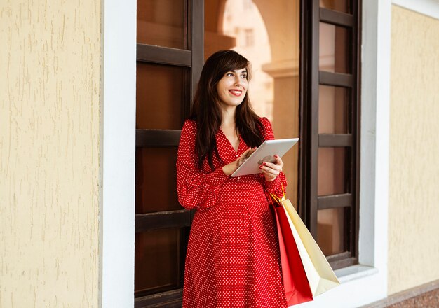 Smiley woman holding shopping bags et tablette