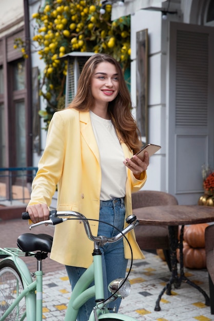 Smiley woman holding smartphone et vélo dans la ville